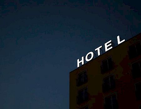A hotel building with a partially illuminated sign reading "HOTEL," set against a dark night sky.