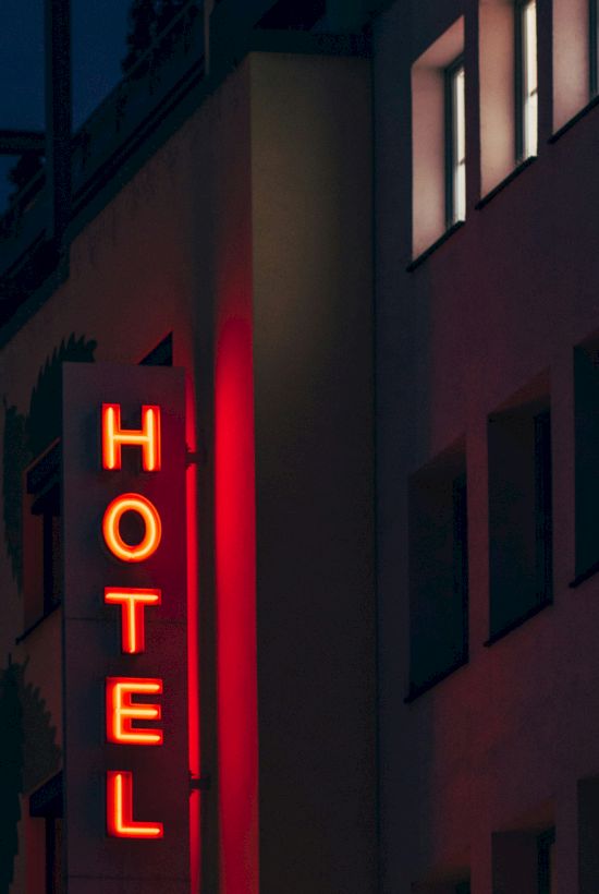 A building with a bright red neon sign displaying the word "HOTEL" at night.